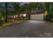 Charming home featuring a two-car garage and inviting front porch, surrounded by lush trees and a spacious driveway at 503 Overbrook Dr, Albemarle, NC 28001