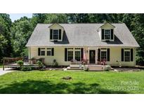 Charming home featuring dormer windows, black shutters, a cozy porch and a lush green front lawn at 7648 Forest Oak Dr, Denver, NC 28037