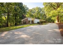 Ranch style home with brick accents, a long driveway, and mature trees surrounding the property at 981 Sherwood Cir, Lancaster, SC 29720