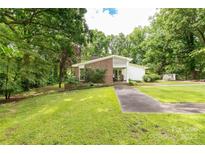 Beautiful single-story home featuring a brick facade and lush landscaping on a green, tree-lined lot at 981 Sherwood Cir, Lancaster, SC 29720