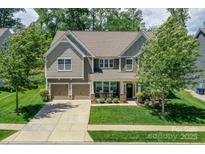 Charming two-story home featuring a manicured lawn, a two-car garage, and a welcoming front porch at 135 Canoe Pole Ln, Mooresville, NC 28117