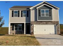 Two-story home features a stone facade, a gray siding exterior, a white garage door and black window shutters at 214 Parker Claire Ln, Kings Mountain, NC 28086