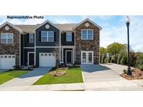 Charming townhome featuring stone accents, a two-car garage, and a well-manicured front lawn and long driveway at 733 Wagon Cross Ct, York, SC 29745
