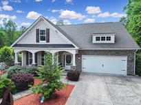 Charming home featuring stone accents, two-car garage, manicured landscaping, and a covered front porch at 7710 Grove Hall Ave, Mint Hill, NC 28227