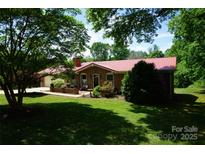 Charming brick home featuring a well-manicured lawn, red roof, and lush greenery at , Hickory, NC 28602