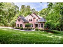 Charming brick home with a well-manicured lawn and lush, mature trees at 112 Eagle Chase Ln, Troutman, NC 28166