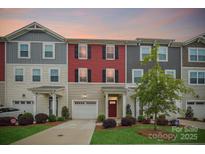 Charming townhome featuring colorful siding, a driveway, manicured lawn, and a covered front porch at 1206 Keydet Dr, Charlotte, NC 28216