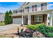 Charming two-story home featuring stone accents, a covered porch, and landscaped front yard with colorful flowers at 142 Wellshire St, Mooresville, NC 28115