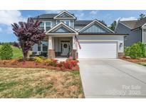 Charming home featuring a two-car garage, covered porch, and beautifully landscaped front yard at 1497 Striped Bass Ln, Clover, SC 29710