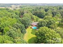 Stunning aerial view of a private backyard with an in-ground pool surrounded by lush greenery at 4805 Nesbitt Rd, Monroe, NC 28112