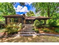 Charming log cabin home featuring stone steps, lush landscaping, and a serene, wooded setting at 6510 Sharon Hills Rd, Charlotte, NC 28210