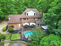 Beautiful brick home featuring a refreshing backyard pool, expansive deck, and mature trees at 8524 Quarters Ln, Mint Hill, NC 28227