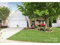Charming home with a lush green lawn and inviting front porch with vibrant red seating at 9814 Fernspray Rd, Charlotte, NC 28215