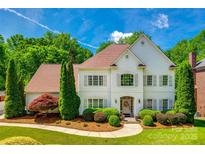 Elegant two-story home featuring a well-manicured lawn, mature trees, and a charming front entrance at 10327 Oak Pond Cir, Charlotte, NC 28277