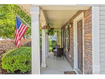 Inviting front porch with stone accents, seating, and an American flag, creating a warm welcome at 111 Tilton Dr, Mooresville, NC 28115