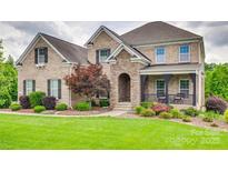Charming brick home features manicured landscaping, stone accents, and inviting front porch at 308 Hollister Estates Dr, Waxhaw, NC 28173