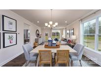 Open-concept dining area showcases a modern chandelier and transitions into a naturally lit living space at 4214 Steel Way, Sherrills Ford, NC 28673
