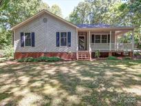 Charming single-story home featuring a covered porch, landscaped front yard, and inviting curb appeal at 4901 Pine Oaks Dr, Monroe, NC 28112