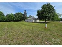 Quaint single-story home featuring a metal roof and a sprawling, well-maintained lawn with mature trees at 5501 Barrier Rd, Concord, NC 28025