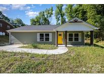 Charming single-story home with a bright yellow front door and neatly landscaped yard at 611 Fernwood Dr, Albemarle, NC 28001