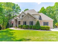 Charming, two-story brick home with blue shutters, landscaped yard, and an American flag at 123 Archbell Point Ln, Mooresville, NC 28117