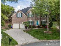 Brick home with two-car garage, lush landscaping, and a blue front door adds curb appeal at 15406 Pepperwood Ct, Huntersville, NC 28078