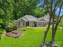Inviting brick home with manicured lawn and lush landscaping, framed by mature trees, creating a serene setting at 160 Fernbrook Dr, Mooresville, NC 28117