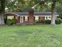 Charming brick home with a well-manicured lawn and mature trees in a quiet neighborhood at 224 Locust Ave, Locust, NC 28097