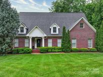 Charming red brick home with manicured lawn, mature trees and dormer windows provides excellent curb appeal at 3015 Hamptonbrook Dr, Gastonia, NC 28056