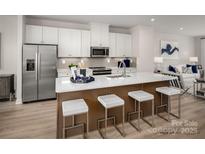 Modern kitchen boasts white cabinets, stainless steel appliances, and a spacious island with seating at 5030 Grain Orchard Rd # 3025C, Indian Trail, NC 28079