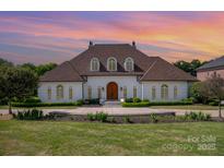 Elegant home with a manicured front lawn and refined landscaping, highlighted by an arched front door at 5400 Challisford Ln, Charlotte, NC 28226