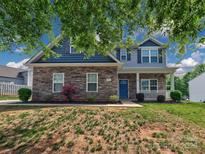 Charming two-story home with a stone facade, blue shutters, and manicured lawn at 6541 Hasley Woods Dr, Huntersville, NC 28078