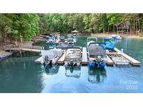 An array of covered boats docked on a serene lake with lush green trees in the background at 7687 Bermuda Hills Ln, Denver, NC 28037