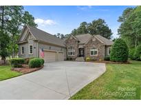 Charming stone-accented home features a three-car garage and manicured landscaping at 7687 Bermuda Hills Ln, Denver, NC 28037