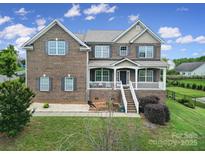 Charming two-story brick home with a welcoming front porch and well-maintained lawn at 9029 Woodview Ct, Fort Mill, SC 29707