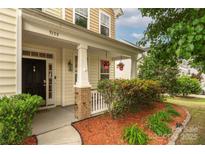 Charming front porch with brick accents, hanging flower baskets, and well-maintained landscaping welcomes you home at 9159 Marasol Ln, Concord, NC 28027