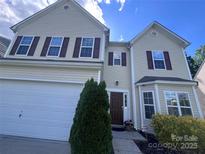 Charming two-story home featuring a well-manicured lawn, a white garage door, and an inviting front entrance at 9321 Bradstreet Commons Way, Charlotte, NC 28215