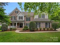 Charming two-story brick home with manicured lawn, decorative shutters, and inviting front porch at 9624 Barnburgh Ln, Huntersville, NC 28078