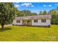 Charming ranch home features a manicured lawn, black shutters, and lovely landscaping at 115 Three Oaks Ln, Statesville, NC 28677