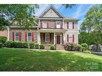 Charming two-story home with stone accents, red shutters and a well-manicured front lawn at 126 W Warfield Dr, Mooresville, NC 28115