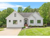 Charming white farmhouse-style home featuring a well-manicured lawn and black-framed windows at 184 Quiet Cove Rd, Mooresville, NC 28117