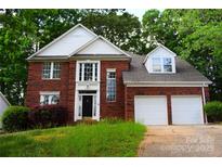 Traditional two-story red brick home with a two-car garage and lush green trees around the house at 2608 Yarrow Rd, Charlotte, NC 28213