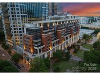 Stunning aerial view of a luxury condo building with brick facade, balconies and park at 435 S Tryon St # 601, Charlotte, NC 28202
