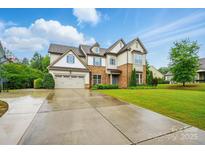 Two-story home featuring a stone and vinyl exterior, lush lawn, and a two-car garage with extended driveway at 5105 Paisano Ln, Waxhaw, NC 28173