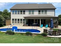 Inviting backyard featuring a sparkling blue pool, covered patio, and ample seating for outdoor entertaining at 5105 Paisano Ln, Waxhaw, NC 28173