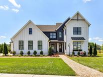 Stunning two-story farmhouse with beautiful landscaping, manicured lawn, brick pathway, and modern black and white accents at 8108 Farm Crossing Ln # 26, Huntersville, NC 28078