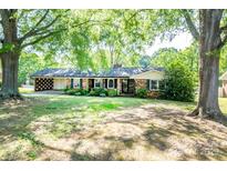 Charming single-story brick home with a covered carport and manicured lawn, shaded by mature trees at 1211 Starlight Dr, Shelby, NC 28152