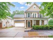 Charming two-story home with a welcoming front porch and stone accents and an attached two-car garage at 13032 Windy Lea Ln, Huntersville, NC 28078