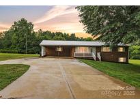Charming brick home with a metal roof, carport, and a spacious driveway at sunset at 133 Jo Monni Loop, Statesville, NC 28625