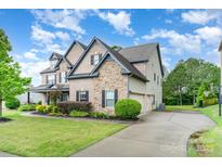 Beautiful two-story home with stone and brick, well-manicured lawn, and three-car garage at 15637 Guthrie Dr, Huntersville, NC 28078